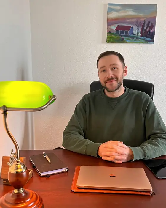 Dimitri Baitinger sitzt mit gefalteten Händen an seinem Schreibtisch
